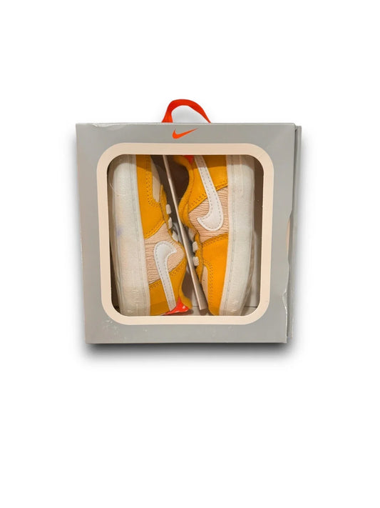 Front view of boxed yellow and white Nike crib shoes